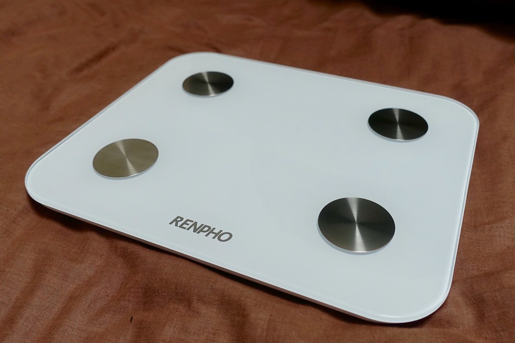 A digital smart scale sitting on a bathroom floor
