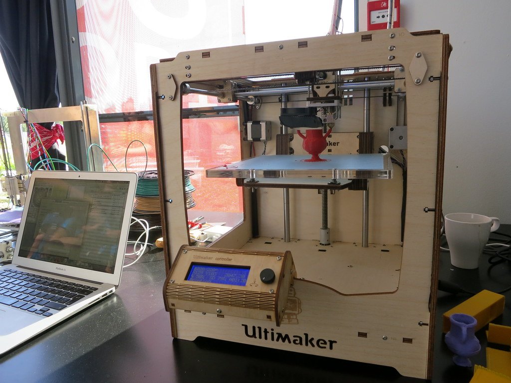 An Ultimaker 3D printer on a desk beside a laptop
