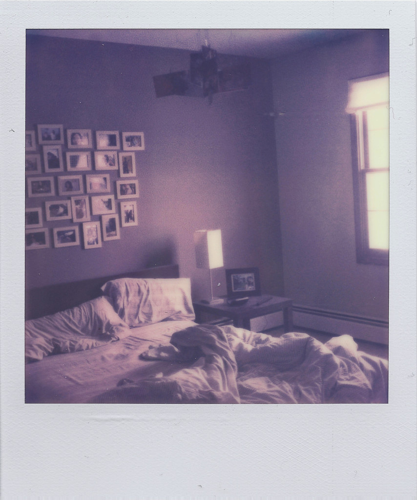 An instant camera ejecting a printed photo, with several developed instant photos nearby