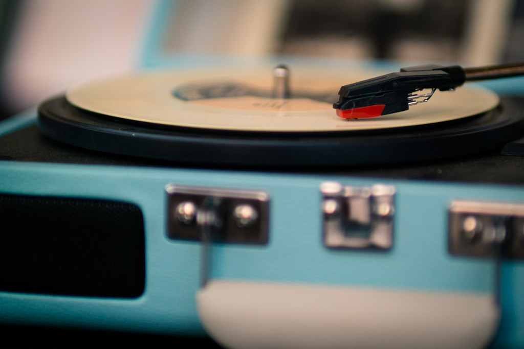 A turntable playing a vinyl record with the tonearm and cartridge visible