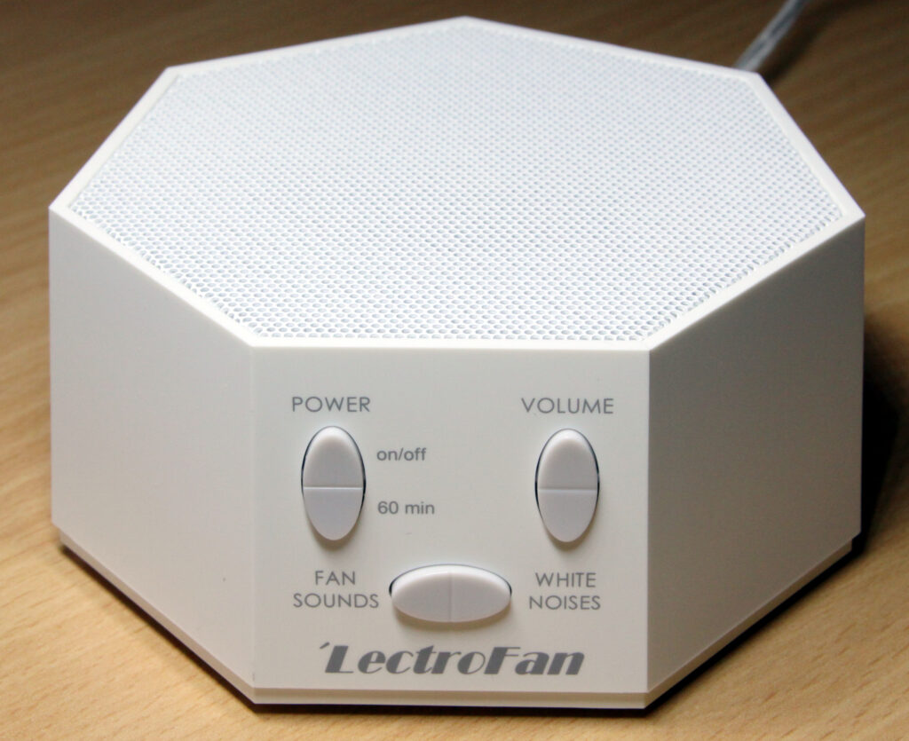 A white noise sound machine on a bedroom nightstand (white noise machine)